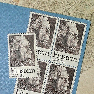 May include: Four vintage United States postage stamps featuring a portrait of Albert Einstein. Each stamp is blue and white and reads "Einstein USA 15c".