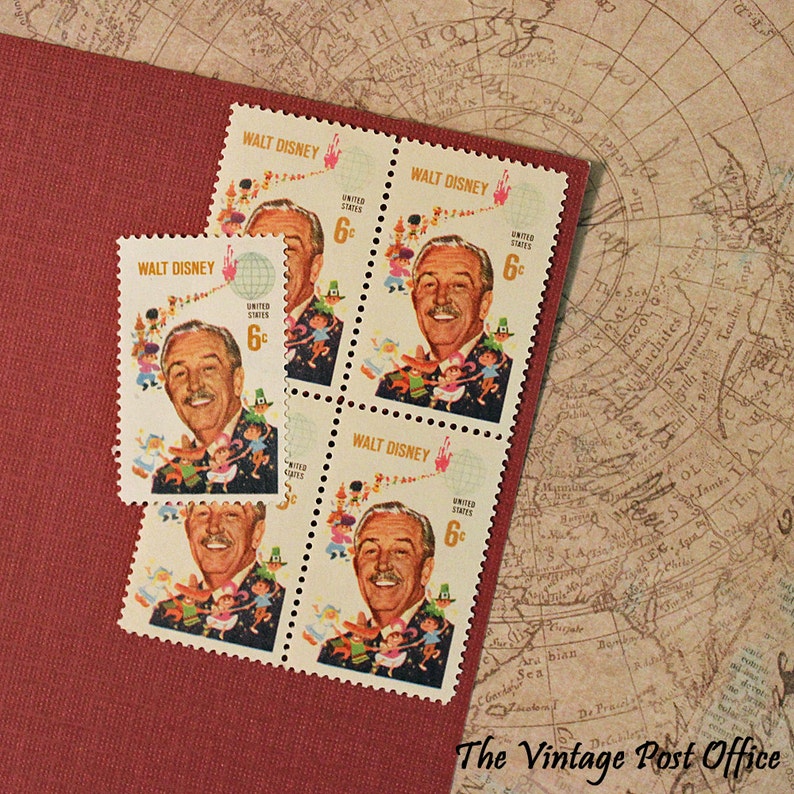 May include: Vintage postage stamps featuring Walt Disney, with a 6-cent denomination. The stamps showcase a portrait of Walt Disney and a colorful illustration of dancing characters. The stamps are on a red surface with a map background.