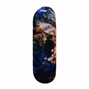 May include: A skateboard deck with a colorful abstract design featuring swirls of blue, orange, and white paint on a black background.