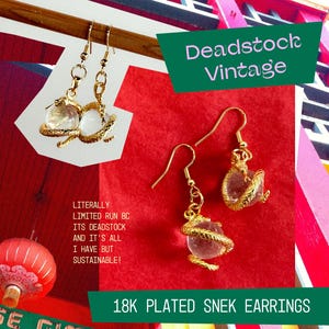 May include: Gold-plated earrings featuring a coiled snake design wrapping around a clear spherical bead. The text on the image reads Deadstock Vintage, 18K PLATED SNEK EARRINGS, LITERALLY LIMITED RUN BC ITS DEADSTOCK AND IT'S ALL I HAVE BUT SUSTAINABLE!, and bchila.etsy.com.