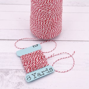 Puede incluir: Una bobina de hilo de panadero rojo y blanco con una etiqueta que dice "8 Yards".