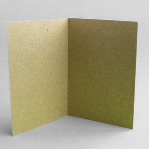 May include: A blank card with a light brown, textured paper surface. The card is folded in half and is open to reveal the inside.