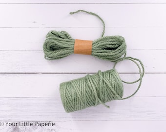 May include: Two spools of green twine on a white wooden surface. The twine is made of natural fibers and is perfect for crafting and decorating.