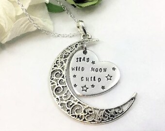 May include: Silver necklace with a crescent moon charm and a heart charm that says "Stay Wild Moon Child".