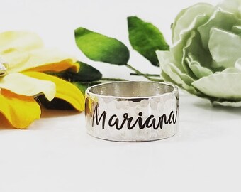May include: A silver hammered ring with the name "Mariana" engraved on it.