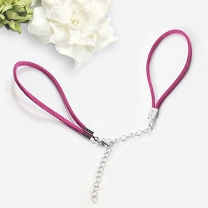 May include: A pink suede cord necklace with a silver chain connector. The necklace has two cords that are connected by a silver chain.