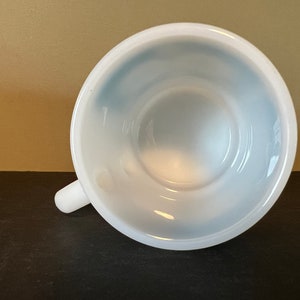 May include: White ceramic mug with a blue interior. The mug is empty and the handle is visible.