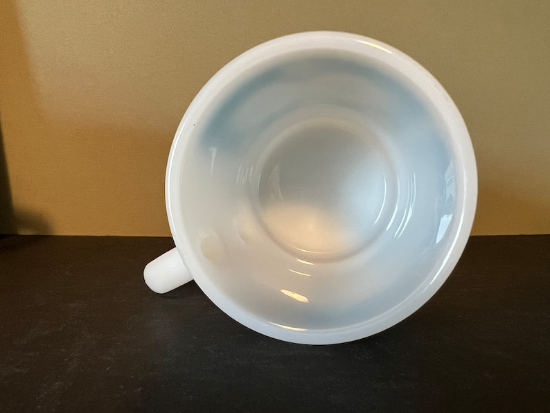 May include: White ceramic mug with a blue interior. The mug is empty and the handle is visible.