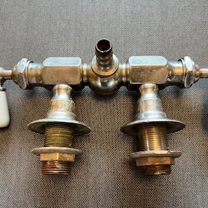 May include: Antique silver-plated double faucet with porcelain handles labelled "HOT" and "COLD".