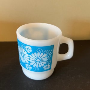 May include: White ceramic mug with a blue and white floral design. The mug has a handle and a rounded bottom.