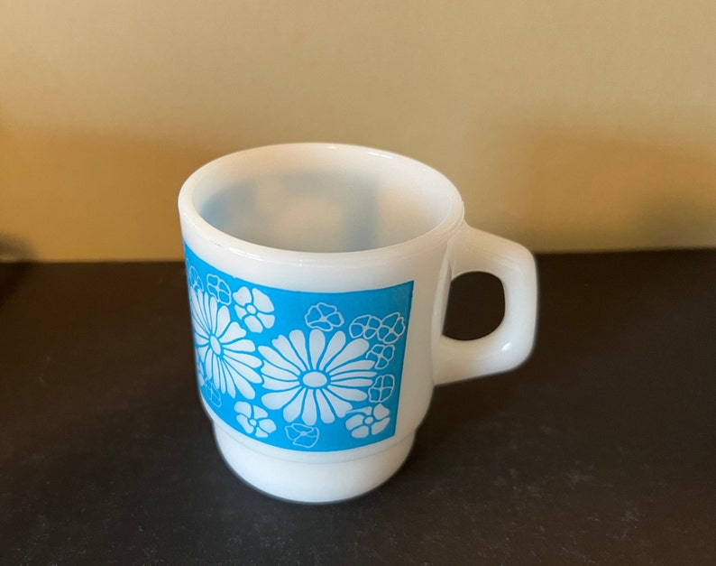 May include: White ceramic mug with a blue and white floral design. The mug has a handle and a rounded bottom.