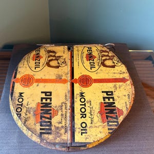 Può includere: Un'insegna pubblicitaria circolare in metallo per olio motore Pennzoil con sfondo giallo, testo e grafica neri. L'insegna mostra il logo Pennzoil, l'illustrazione di un gufo e la scritta 100% Pure Pennsylvania Double Refined Motor Oil.
