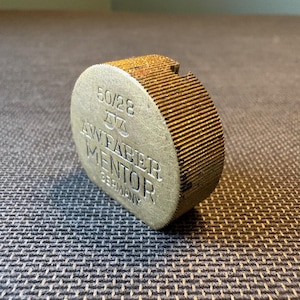 May include: A white ceramic mug with a black handle and the text "But First, Coffee" in a bold, black font. The mug is set against a blurred background, highlighting its clean design.