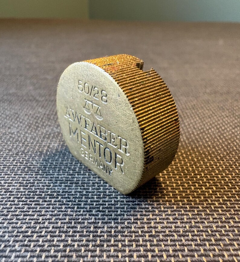 May include: A white ceramic mug with a black handle and the text "But First, Coffee" in a bold, black font. The mug is set against a blurred background, highlighting its clean design.