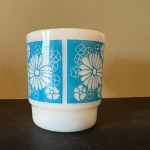 May include: White ceramic mug with a blue and white floral pattern. The mug has a wide base and a rounded top.