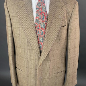 May include: A brown plaid blazer with a white collared shirt and a red paisley tie. The blazer has a classic fit with a notched lapel and two front pockets. The tie features a blue and white paisley pattern.