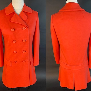 May include: A bright orange double-breasted coat with a skirt. The coat has a collar and long sleeves.