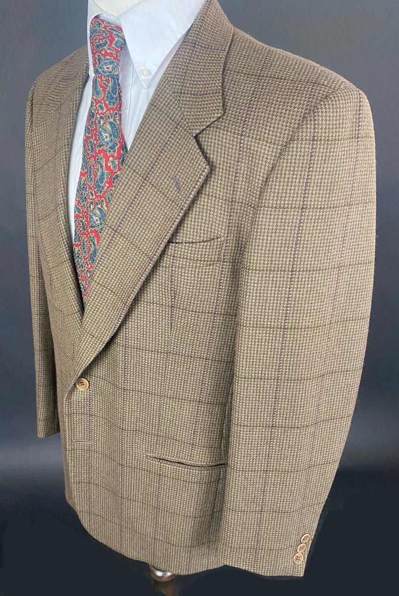 May include: A brown plaid blazer with a white dress shirt and a patterned tie. The blazer has a two-button closure and a notched lapel. The tie features a red and blue paisley design.