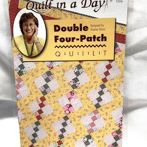 May include: Quilt in a Day pattern for a Double Four-Patch quilt. The pattern features a yellow background with a floral print and a patchwork design in red, pink, green, and black.
