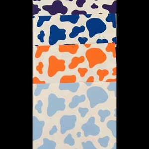 May include: Five fabric swatches with a cow print pattern. The swatches are in different colors: light blue, purple, blue, orange, and a lighter shade of blue.