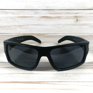 Pu&ograve; includere: Occhiali da sole neri con montatura rettangolare spessa e lenti scure. Gli occhiali da sole hanno un design elegante e moderno, adatti per attivit&agrave; all'aperto. La montatura &egrave; in materiale nero opaco.
