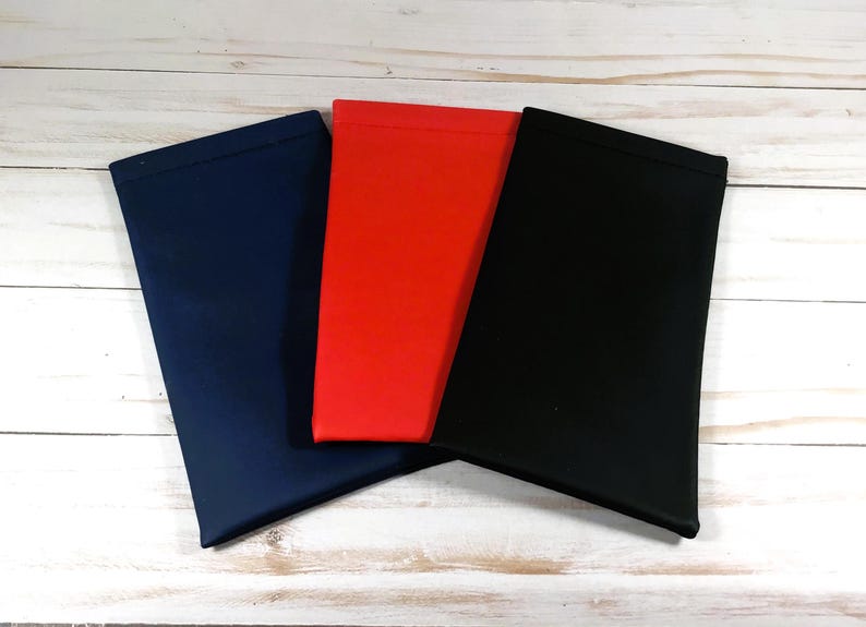 Pode incluir: Tr&ecirc;s bolsas de tecido em azul marinho, vermelho e preto. As bolsas est&atilde;o dobradas e empilhadas umas sobre as outras.