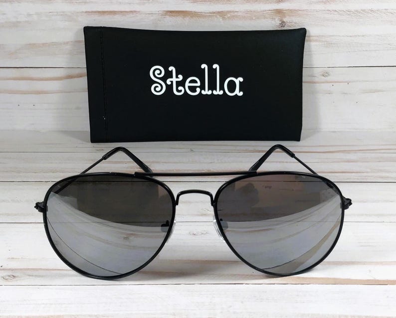 May include: Black aviator sunglasses with mirrored lenses and a black case with the word "Stella" printed in white.