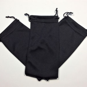 May include: Three black drawstring pouches made of soft fabric. The pouches are folded and stacked on top of each other.
