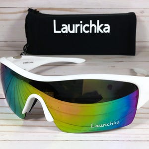 May include: White wraparound sunglasses with a rainbow iridescent lens and the word "Laurichka" printed on the frame.