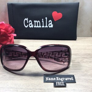 Peut inclure: Lunettes de soleil de couleur bordeaux avec un motif g&eacute;om&eacute;trique sur les verres. Les lunettes de soleil sont dans un &eacute;tui noir avec le nom "Camila" et un c&oelig;ur rouge imprim&eacute; dessus. L'&eacute;tui a &eacute;galement une &eacute;tiquette qui dit "Nom grav&eacute; GRATUIT".