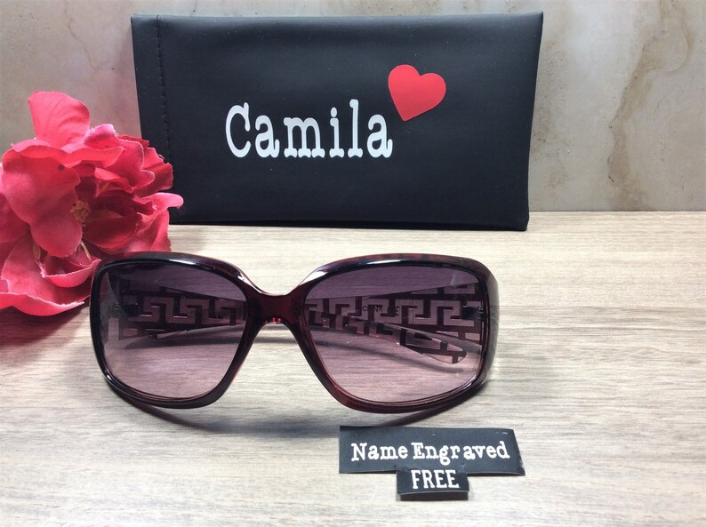 Peut inclure: Lunettes de soleil de couleur bordeaux avec un motif g&eacute;om&eacute;trique sur les verres. Les lunettes de soleil sont dans un &eacute;tui noir avec le nom "Camila" et un c&oelig;ur rouge imprim&eacute; dessus. L'&eacute;tui a &eacute;galement une &eacute;tiquette qui dit "Nom grav&eacute; GRATUIT".