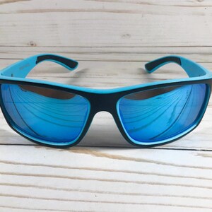 K&ouml;nnte beinhalten: Blaue und schwarze Sonnenbrille mit verspiegelten Gl&auml;sern. Die Sonnenbrille hat ein sportliches Design und ist perfekt f&uuml;r Outdoor-Aktivit&auml;ten.