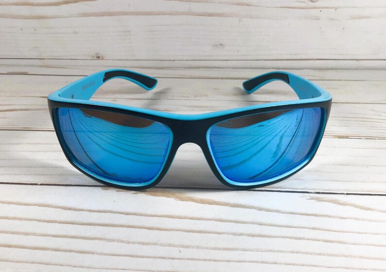 K&ouml;nnte beinhalten: Blaue und schwarze Sonnenbrille mit verspiegelten Gl&auml;sern. Die Sonnenbrille hat ein sportliches Design und ist perfekt f&uuml;r Outdoor-Aktivit&auml;ten.
