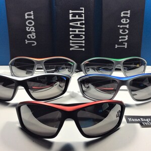 Puede incluir: Cuatro pares de gafas de sol con montura plateada y diferentes acentos de color. Las gafas de sol tienen lentes oscuras y est&aacute;n dispuestas en fila sobre una superficie blanca. El texto "Nombre grabado GRATIS" es visible en la esquina inferior derecha de la imagen.