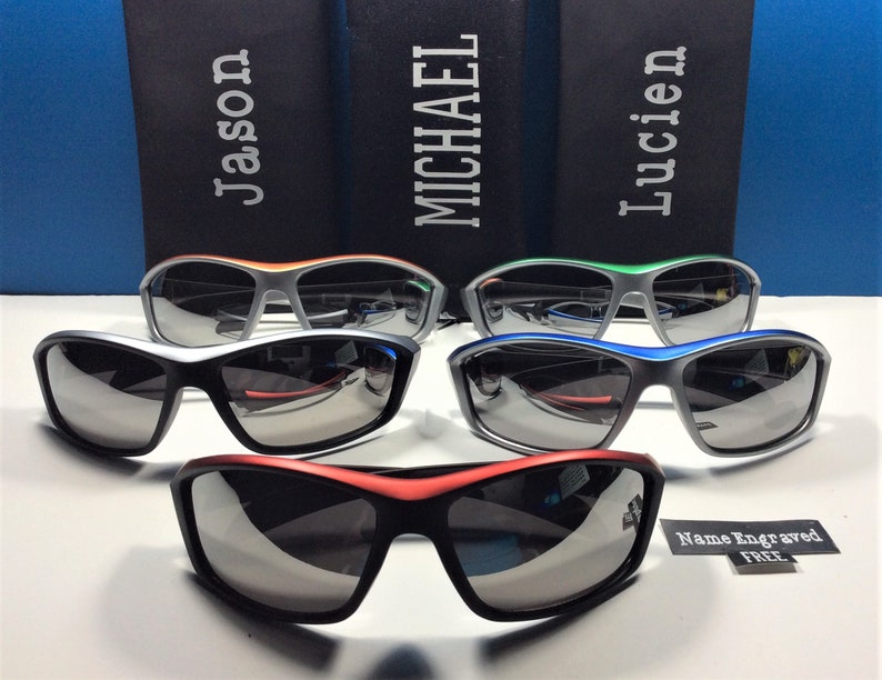 Puede incluir: Cuatro pares de gafas de sol con montura plateada y diferentes acentos de color. Las gafas de sol tienen lentes oscuras y est&aacute;n dispuestas en fila sobre una superficie blanca. El texto "Nombre grabado GRATIS" es visible en la esquina inferior derecha de la imagen.