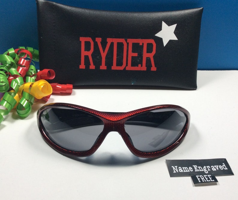 May include: Red and black sunglasses with a star on the case. The case has the name "RYDER" printed on it in red letters. The sunglasses come with a free name engraving.