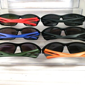 May include: Six pairs of black sunglasses with different colored frames. The frames are red, blue, green, and orange.