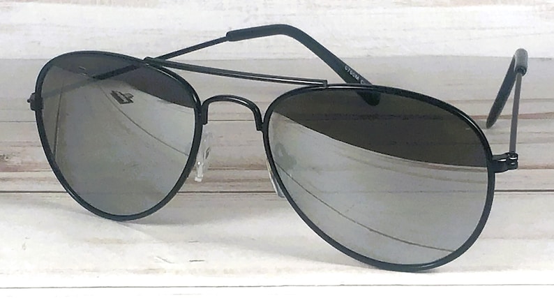 May include: Aviator sunglasses featuring a thin black metal frame and a double bridge design. The lenses are reflective and silver in color, providing a mirrored finish. The temples are black with curved ends, and the nose pads are clear and adjustable.