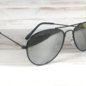 May include: Aviator sunglasses featuring a thin black metal frame and reflective silver mirrored lenses. The design includes a double bridge across the top and slender black temples with curved ends, providing a classic look with a metallic finish.
