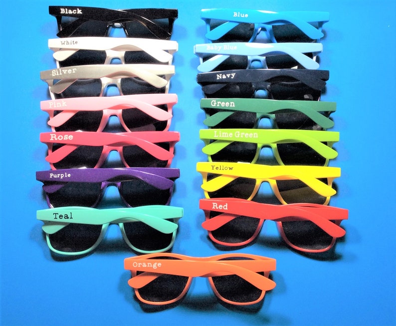 May include: A set of 15 pairs of sunglasses in various colours, including black, white, silver, pink, rose, purple, teal, orange, yellow, red, blue, baby blue, navy, green, and lime green. Each pair has a different coloured frame and black lenses.