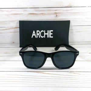 May include: Black sunglasses with a black case that says "ARCHIE" on it.