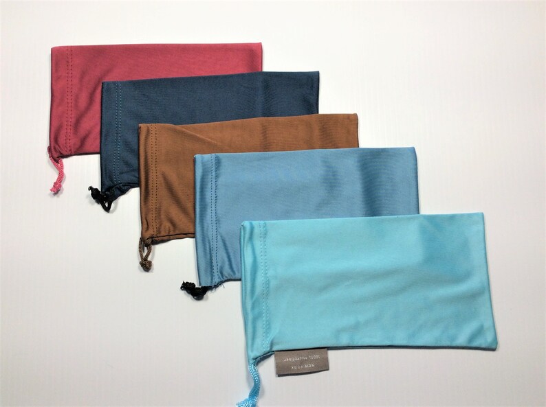 May include: Five different colored drawstring pouches for glasses. The pouches are lined up from top to bottom in the following order: red, dark blue, brown, light blue, and turquoise.