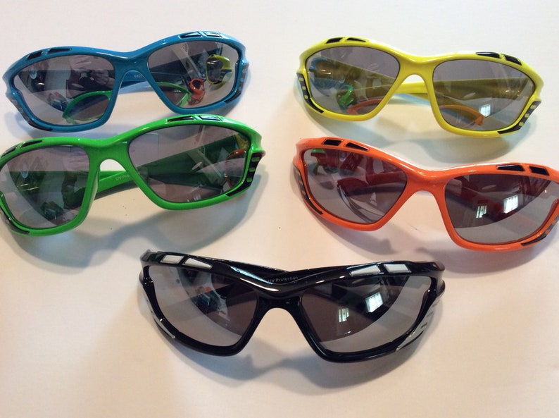 May include: Four pairs of sunglasses with different colored frames: blue, green, orange, and black. All sunglasses have a similar style with a sporty design and gray lenses.