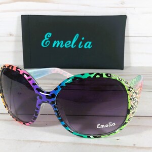 May include: Rainbow leopard print sunglasses with rhinestones and a black case with the word "Emelia" printed on it.