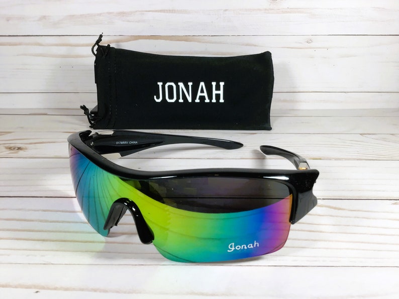 May include: Black sunglasses with a rainbow iridescent lens and a black carrying case with the name "JONAH" printed on it.