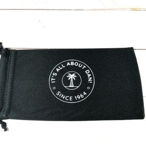 May include: Black drawstring pouch with a white logo that says "It's All About Dan! Since 1964" and a palm tree graphic.