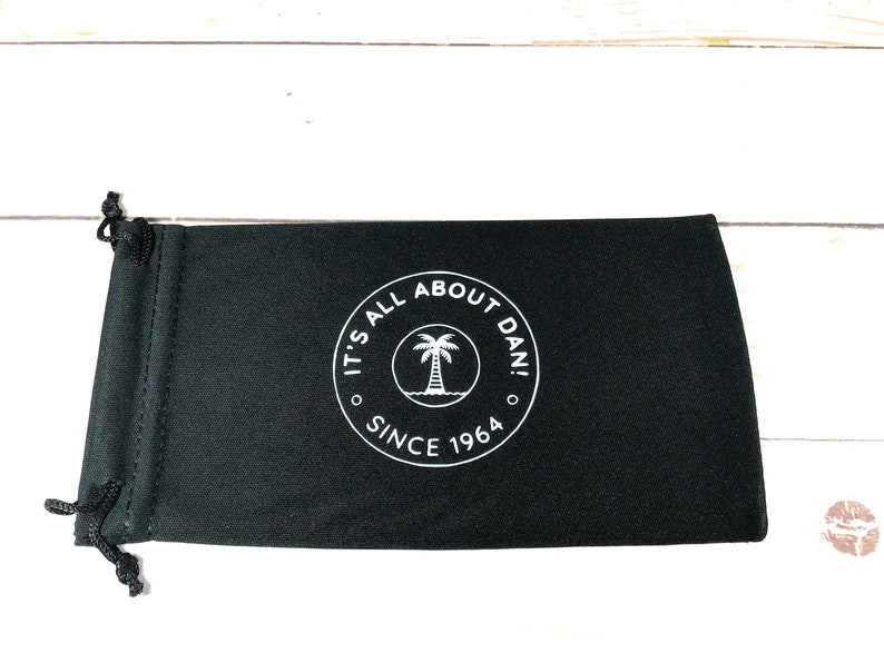 May include: Black drawstring pouch with a white logo that says "It's All About Dan! Since 1964" and a palm tree graphic.