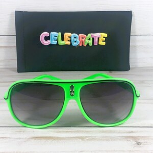 Puede incluir: Gafas de sol de aviador verde brillante con lentes oscuras. Detr&aacute;s de las gafas de sol hay un estuche negro con la palabra "CELEBRATE" en letras coloridas. Las gafas de sol tienen un dise&ntilde;o audaz y moderno.