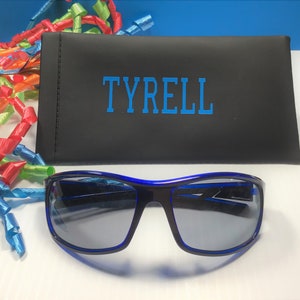 K&ouml;nnte beinhalten: Blaue Sonnenbrille mit schwarzem Rahmen und blauen Gl&auml;sern in einem schwarzen Etui mit dem Namen "TYRELL" in blau.