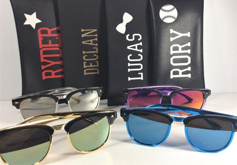 May include: Four personalized sunglass cases with different designs, including a star, a bow tie, a baseball, and the names "Ryder", "Declan", "Lucas", and "Rory".  The cases are black with white lettering.  Four pairs of sunglasses with different colored lenses are shown in front of the cases.